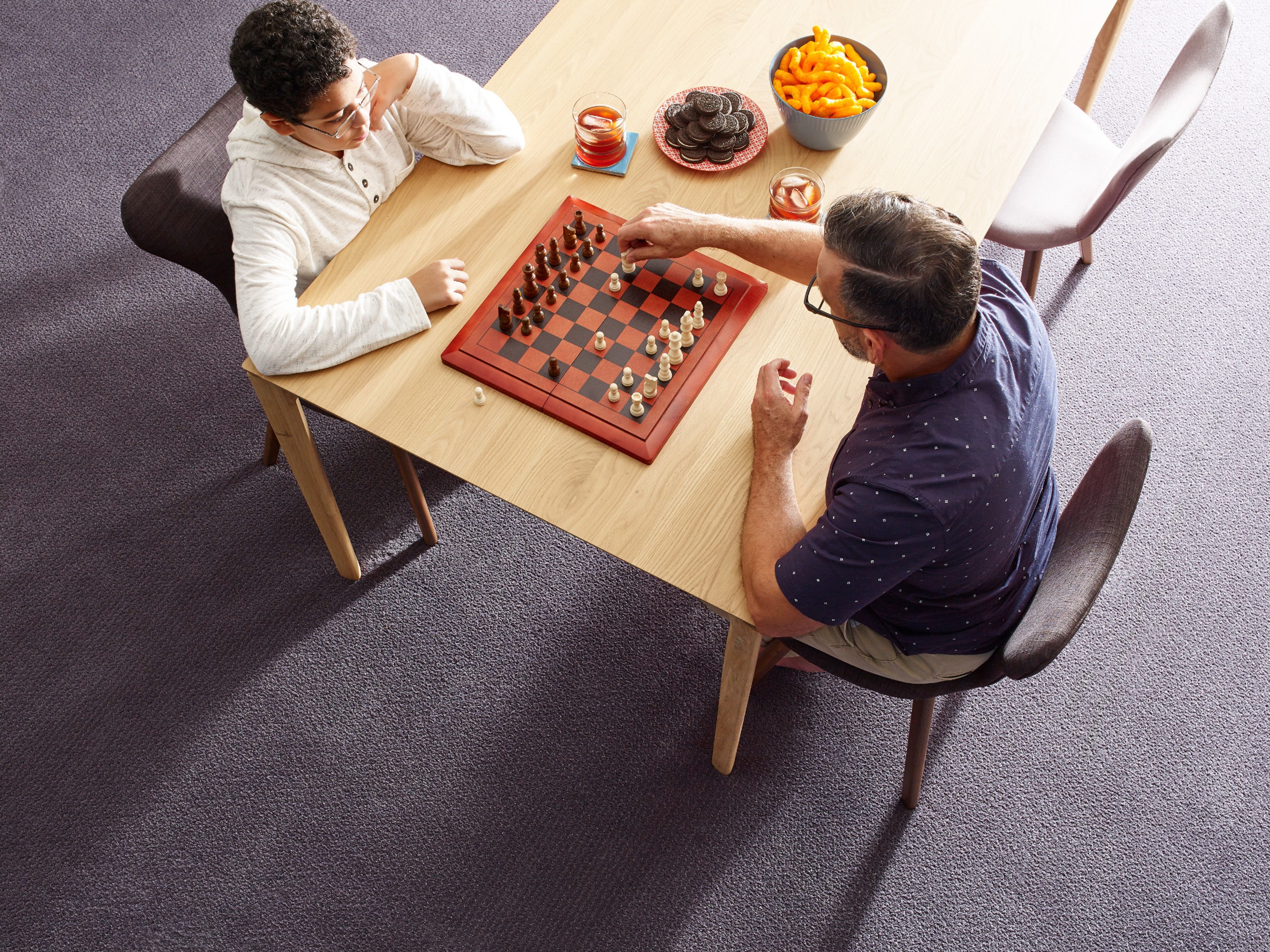 father and son playing chess on wooden table